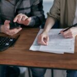 Two People Doing Paperwork and Computing Taxes