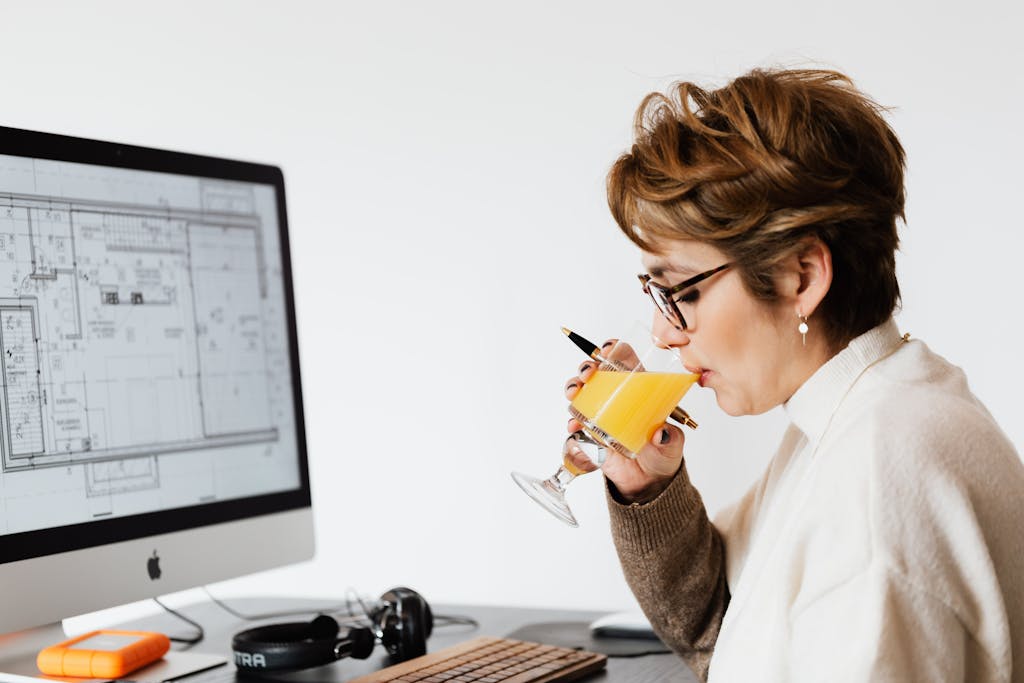 Female architect drinking juice while working on new project