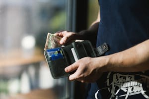 Close-up of a man holding a wallet with cash and credit cards, indoors.